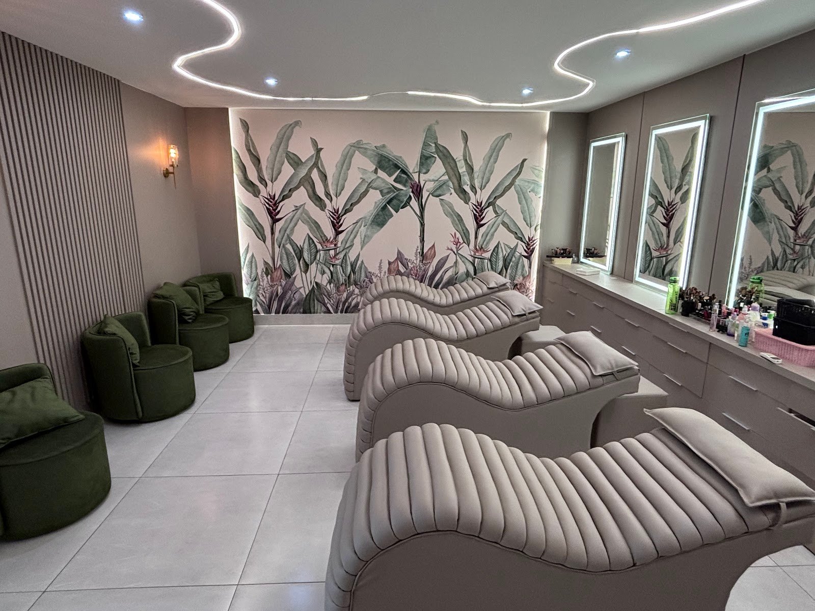 Sala do spa capilar com macas estofadas, poltronas de veludo verde e mural botânico