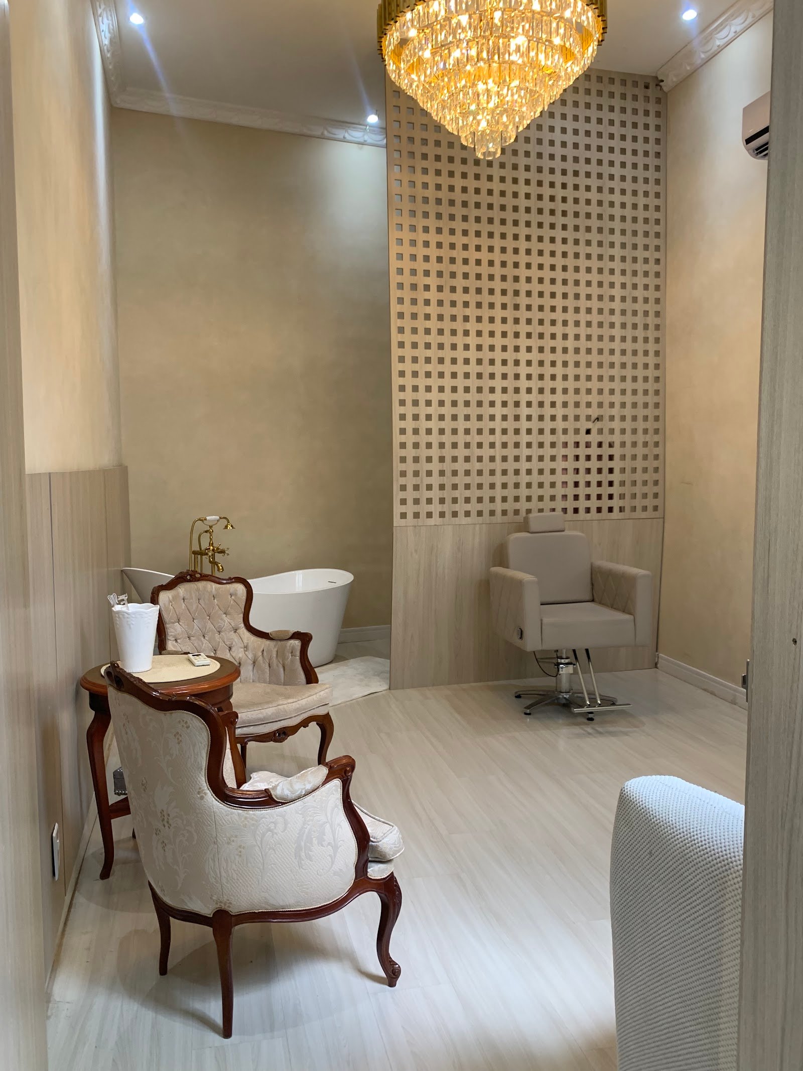 Suíte da noiva com lustre de cristal, banheira branca e poltronas clássicas